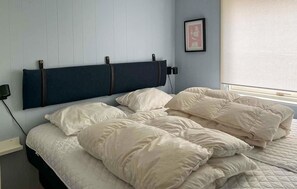 A bedroom with a bed, pillows, a headboard, a wall-mounted lamp, and a window with blinds. - Amazing home in Ansager with WiFi (Ansager)