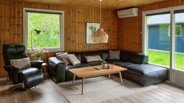 A wooden-paneled room with a leather sofa, a wooden coffee table, and a black leather chair. - Amazing home in Ansager with WiFi (Ansager)