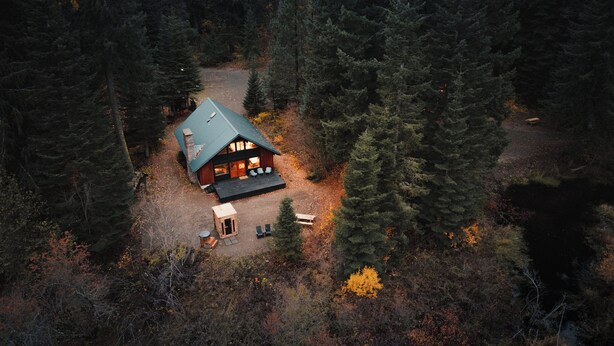 A cabin with a porch, surrounded by dense forest. - Huckleberry House At The Yakima River Club! (Easton)