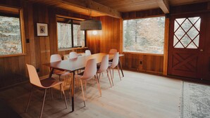 A wooden interior with a dining table and chairs, large windows, and a door with a diamond pattern. - Huckleberry House At The Yakima River Club! (Easton)