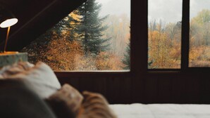 A bedroom with a large window overlooking a forest. - Huckleberry House At The Yakima River Club! (Easton)
