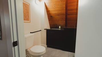 Un baño pequeño con inodoro, lavamanos y techo de madera.