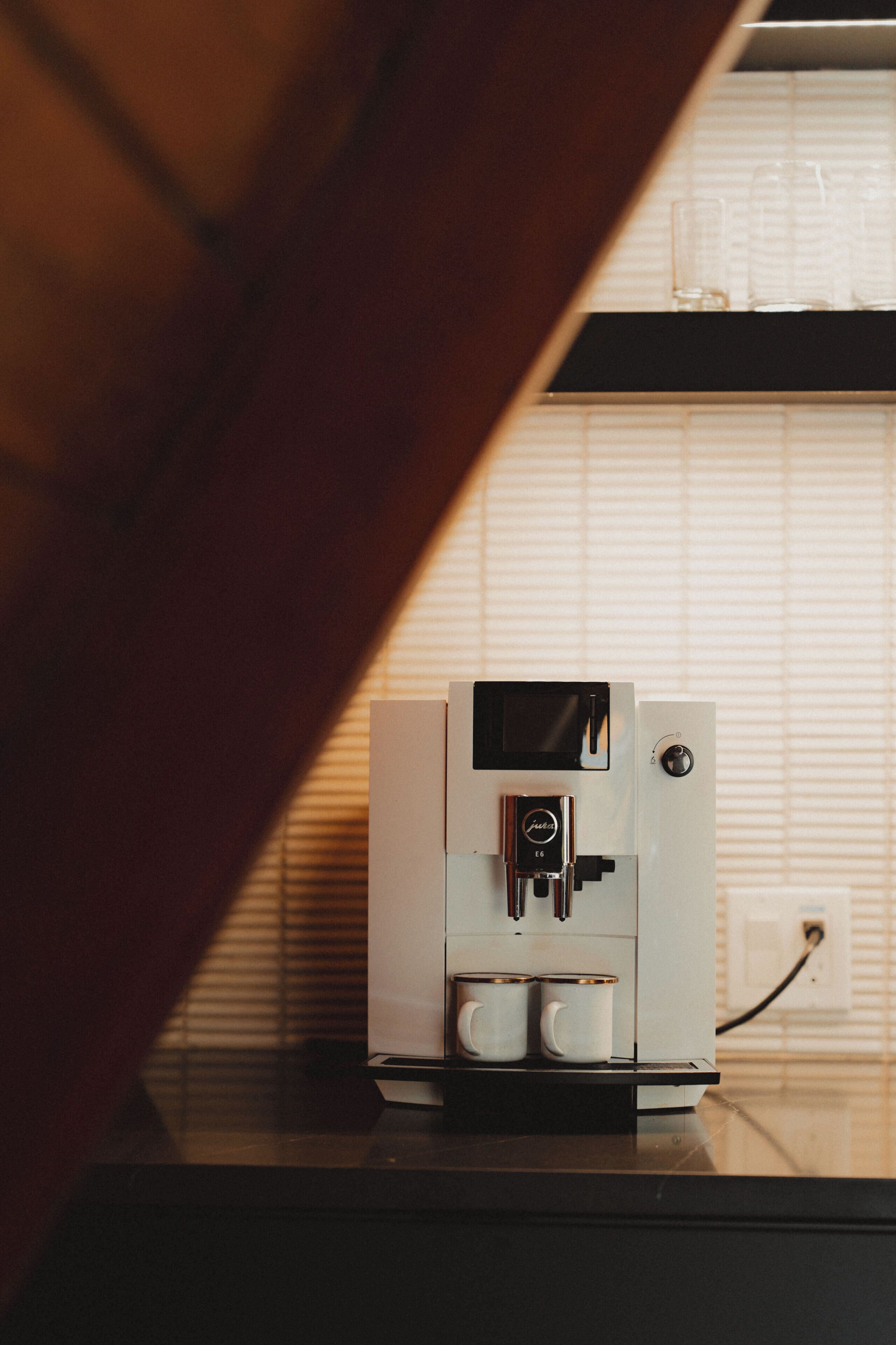 A coffee machine on a countertop with a window in the background.