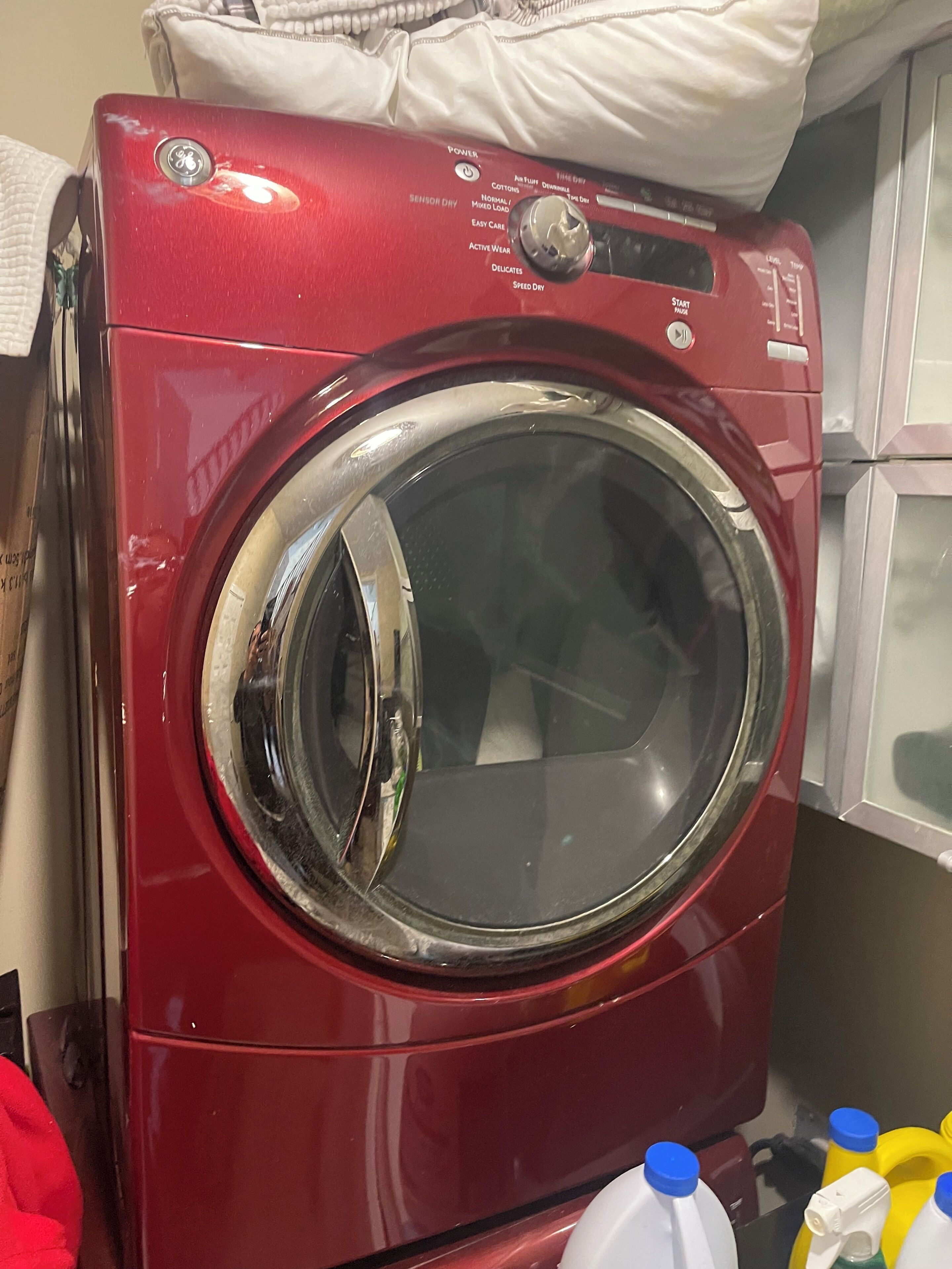 A red front-loading washing machine with a control panel and a transparent door.