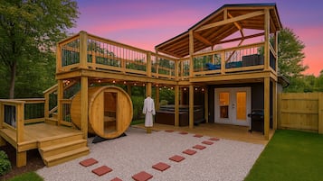 Une structure extérieure en bois à plusieurs niveaux, comprenant un sauna, un jacuzzi et un espace salon extérieur.