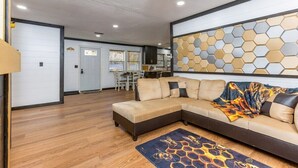A modern living room with a sectional sofa, a dining area, and a kitchen in the background.
