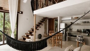 A spacious living area with a hammock, a staircase, and a kitchen area. - Ikal Bungalows: HA is a poolside bungalow with AC in a jungle setting of Tulum. (Tulum)