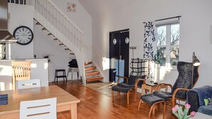 A spacious living area with a wooden staircase, a dining table, and a cozy seating arrangement.