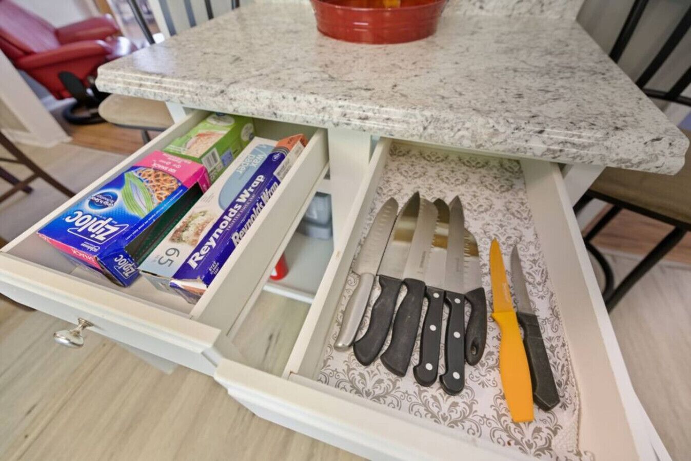 Un tiroir de cuisine contenant divers articles, notamment une boîte de sacs de type Ziploc, une boîte de papier d’aluminium Reynolds Wrap et plusieurs couteaux.