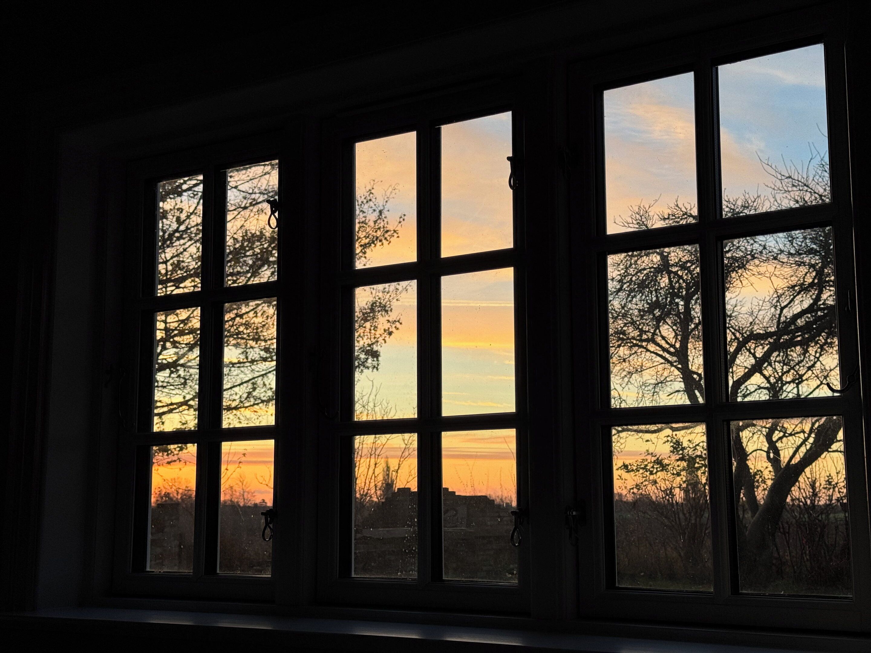 Una habitación con un ventanal grande que da a un paisaje al atardecer.