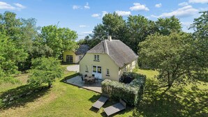 Ein Haus mit Terrasse, einer kleinen Holzterrasse und einem Rasen.