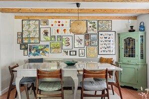 A dining area with a white table, wooden chairs, and a green cabinet. - Secluded cottage in idyllic surroundings (Harpelunde)