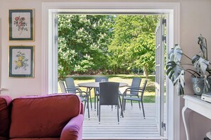 Ein Zimmer mit einer Schiebetür, die auf eine Terrasse mit Tisch und Stühlen führt.