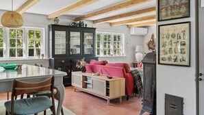 Ein Zimmer mit Esstisch, Stühlen, einer Couch, einem Schrank und einem Kamin.