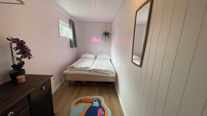 Una camera da letto con un letto, una cassettiera, uno specchio, una finestra e un'insegna luminosa al neon.