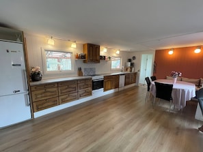 Una cocina con armarios de madera, un refrigerador, una estufa y un comedor con mesa y sillas.