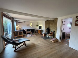 Ein großzügiger Wohnbereich mit Sofa, Lounge-Sessel, Couchtisch und Kamin.