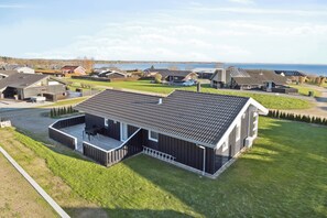 A modern house with a large deck, a view of the sea, and a well-maintained lawn. - Seaview cottage with sauna near the beach (Sjølund)