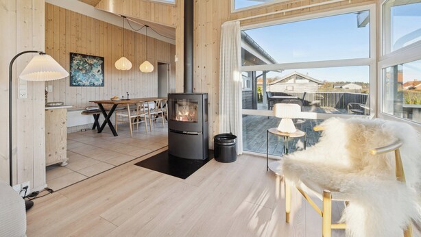 Un interior moderno con estufa de leña, paredes de madera y ventanas amplias, además de un comedor.