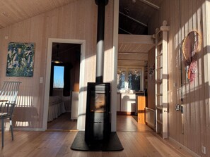 A wooden interior with a fireplace, a dining area, and a kitchen. - Inviting summer house on scenic Røsnæs (Kalundborg)