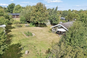 Ein Wohnhaus mit großem Rasen, einer Holzterrasse und einem Satteldach.