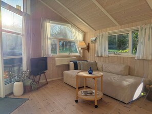 A cozy room with wooden walls, a sofa, a TV, and a lamp. - Inviting summer house on scenic Røsnæs (Kalundborg)