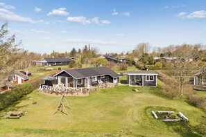Een woonwijk met meerdere huizen, een schommel en een klein zitgedeelte buiten.