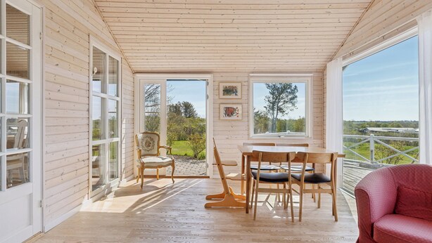 Un intérieur en bois comprenant un coin repas, des chaises et un canapé rouge.