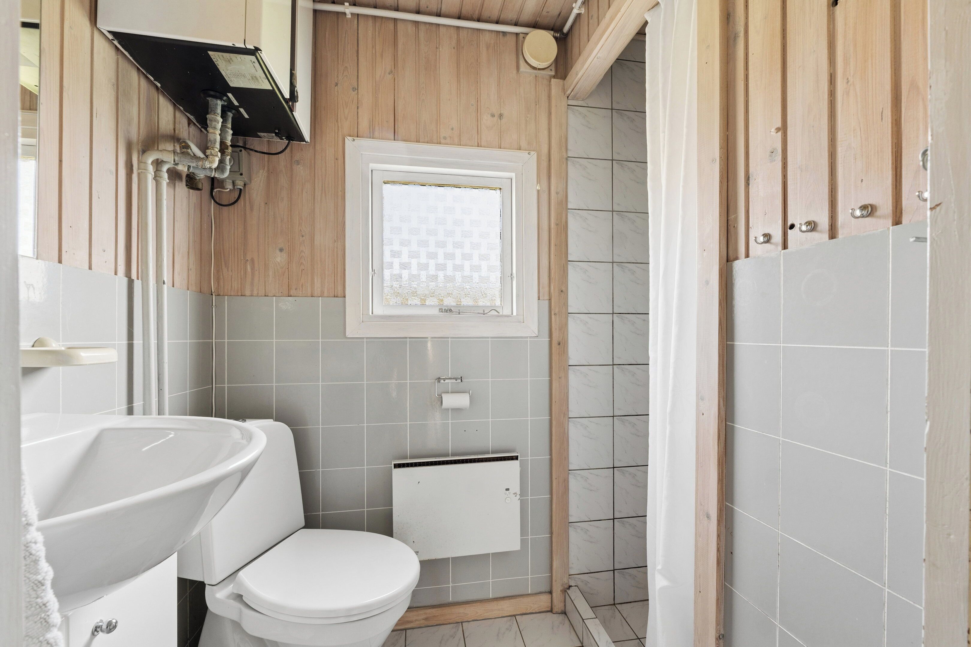 A bathroom with a toilet, sink, and shower area.