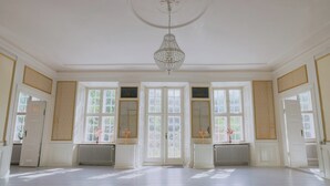 A spacious room with large windows, a chandelier, and a radiator. - Hindemae Estate for holidays and events (Ullerslev)