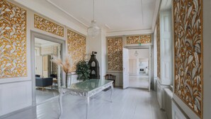 A spacious hallway with a glass-top table, a decorative vase, and a chandelier. - Hindemae Estate for holidays and events (Ullerslev)