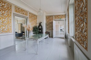 Un hall dâentrĂ©e spacieux, agrĂ©mentĂ© dâune table Ă plateau de verre, dâun vase dĂ©coratif et dâun lustre.