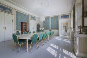 Ein formeller Speisesaal mit einem langen Tisch, Stühlen und einer Kandelaber.