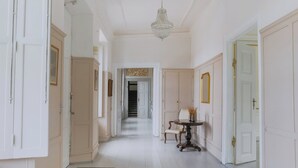 A hallway with white walls, a chandelier, and a door at the end. - Hindemae Estate for holidays and events (Ullerslev)