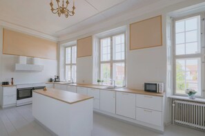 Une cuisine moderne avec des meubles blancs, un plan de travail en bois et un four encastré.