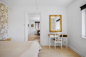 A bedroom with a bed, a desk with a chair, a mirror, and a door leading to another room. - Bright modern holiday home near Hindemae (Ullerslev)