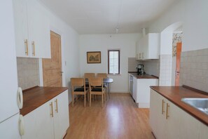 A kitchen with wooden cabinets, a dining table with chairs, a window, and a painting on the wall. - Bright modern holiday home near Hindemae (Ullerslev)
