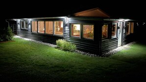 Een huis in blokhutstijl met grote ramen, een overdekte veranda en een verzorgd gazon.