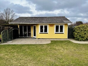 Un bùtiment jaune avec un toit en tuiles, une enseigne indiquant « BOTNIA » et une terrasse dallée.