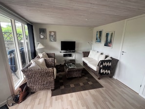 A living room with wicker furniture, a flat-screen TV, and artwork on the walls.