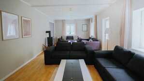 Un salon moderne avec un canapé, une table basse et, au fond, un coin repas.