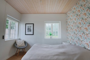 A bedroom with a bed, two windows, a chair, and a framed picture on the wall. - Stay in Hindemaes historic managers house (Ullerslev)