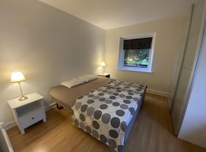 A bedroom with a bed, two bedside tables, a window with a view, and a door. - The coziest farm holiday in the countryside (Tommerup)