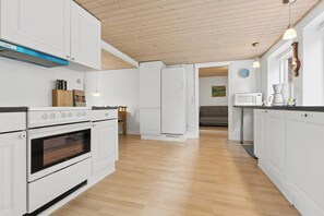 Una cocina moderna con armarios blancos, horno integrado y microondas.