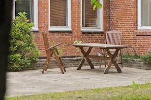 Un bâtiment en briques avec un banc et une table en bois devant.