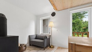 Habitació acollidora amb sofà, làmpada, taula i finestra amb vista a vegetació.