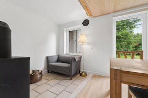 Une pièce confortable avec un canapé, une lampe, une table et une fenêtre donnant sur un paysage verdoyant.