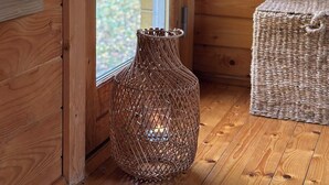 En inredning med trädetaljer, en flätad vas och en flätad korg på golvet.