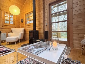 Ein gemütliches Blockhaus-Interieur mit Kamin, einem weißen Tisch mit Kerze und einem großen Fenster.