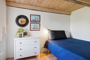 A bedroom with a bed, a white dresser with drawers, a mirror, and two framed pictures on the wall. - Holiday apartment with sea view on Strynø (Rudkøbing)